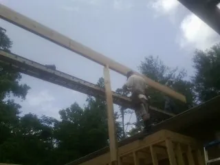 Carpenter setting a ridge beam over a new addition frame — Ice Dam Removal by Roofing Brothers in Moody