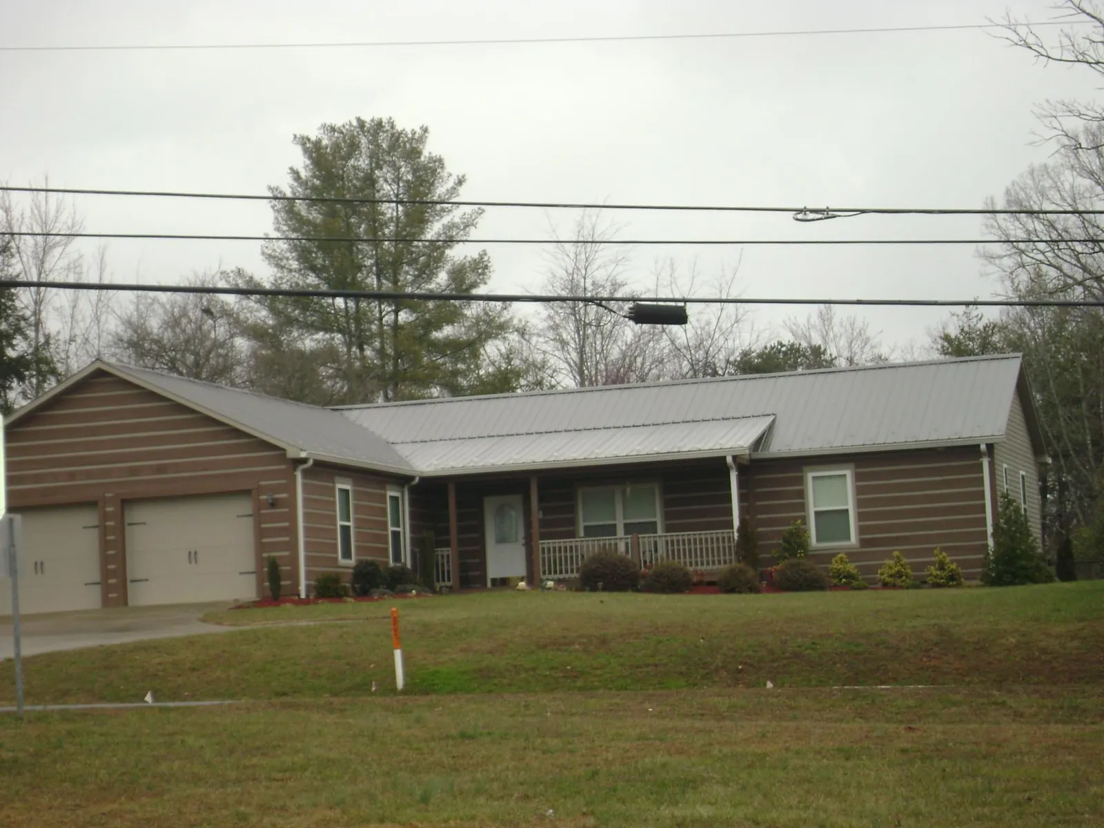 Gray metal roof on a log sided ranch home with a front porch in Moody
