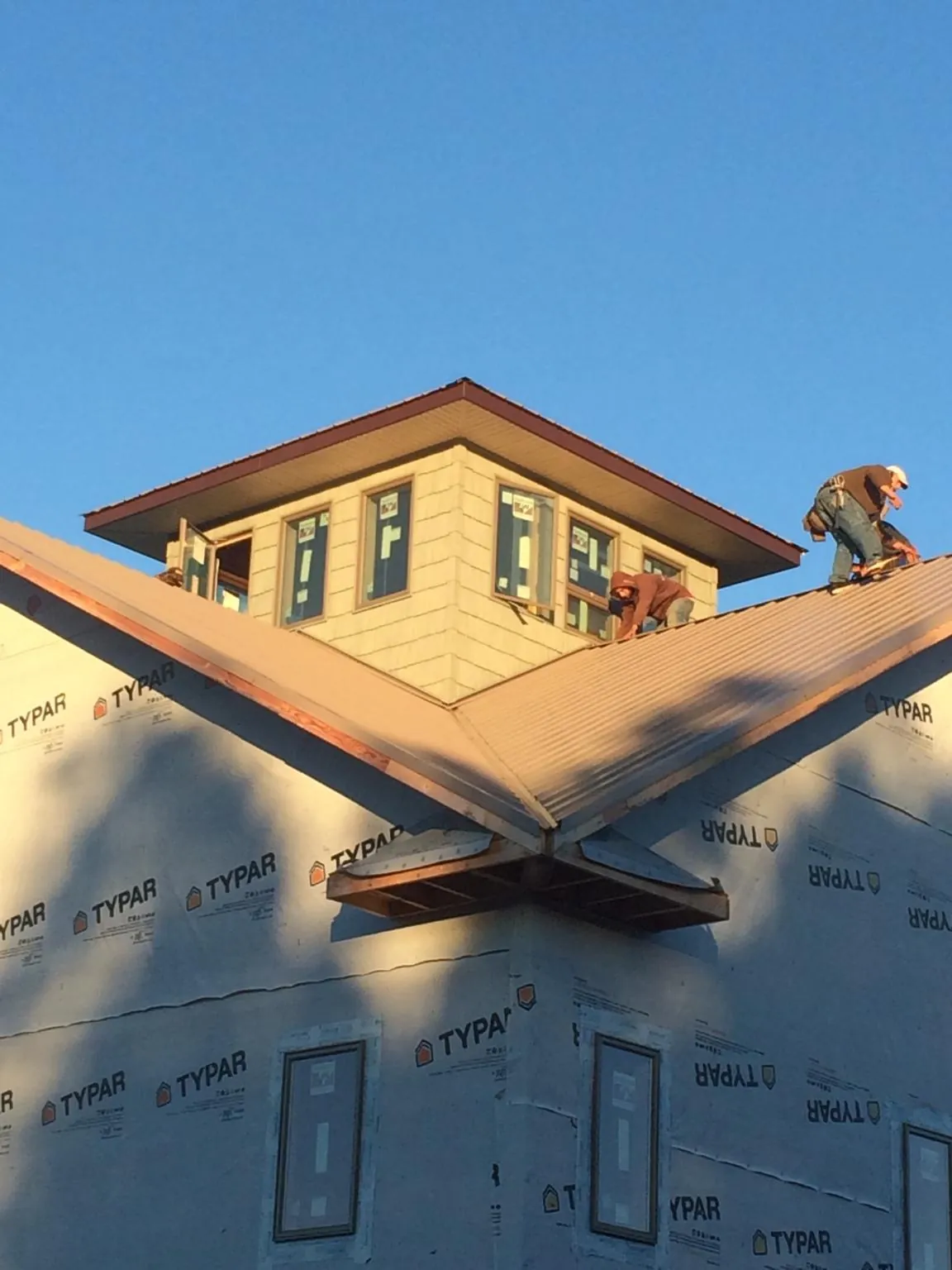 Roofers working around a rooftop cupola on a new metal roof at sunset — Roof Waterproofing in Moody by Roofing Brothers